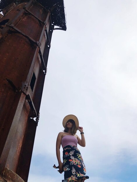 Foto vista de ángulo bajo de una mujer de pie junto a una estructura construida contra el cielo