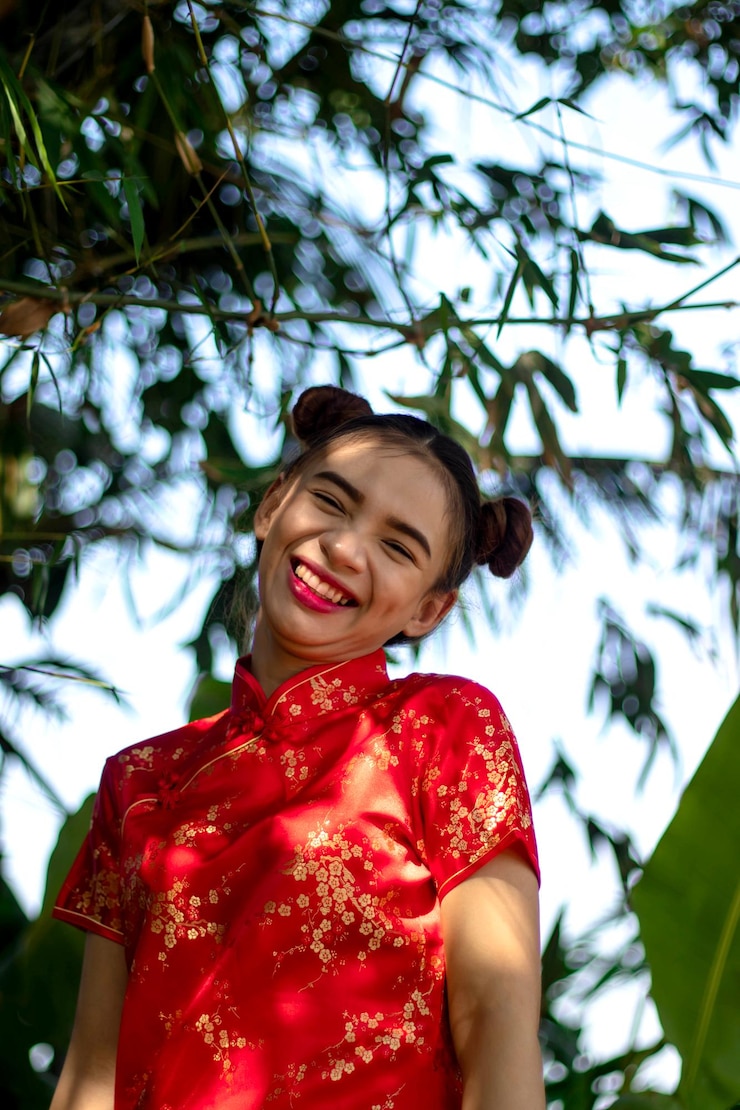 Foto vista de ángulo bajo de una mujer sonriente contra los árboles