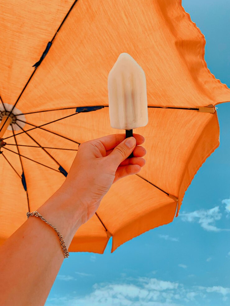 Foto vista de ángulo bajo de una mujer sosteniendo un paraguas contra el cielo naranja