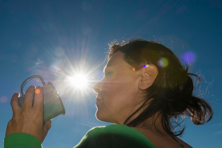 Foto vista de bajo ángulo de una mujer sosteniendo una taza contra el sol brillante