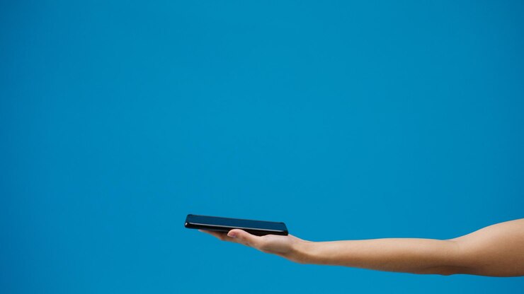 Foto vista de bajo ángulo de una mujer usando un teléfono móvil contra un cielo azul claro