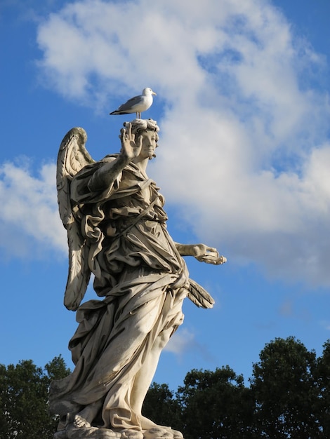 Foto vista de ángulo bajo de un pájaro posado en una estatua contra el cielo