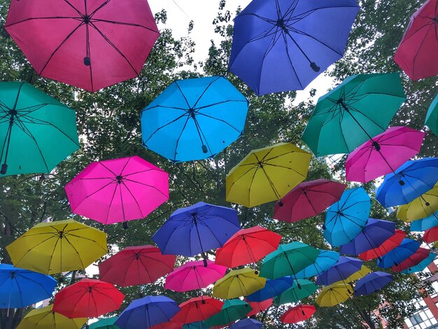 Foto vista de ángulo bajo de paraguas multicolores colgando contra el cielo azul