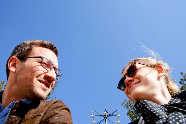 Vista de ángulo bajo de una pareja sonriente contra un cielo azul claro