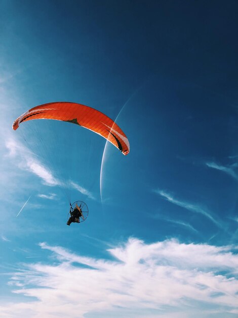 Vista en bajo ángulo de una persona en parapente contra el cielo azul