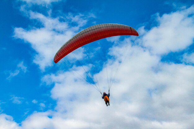 Vista en bajo ángulo de una persona en parapente contra el cielo