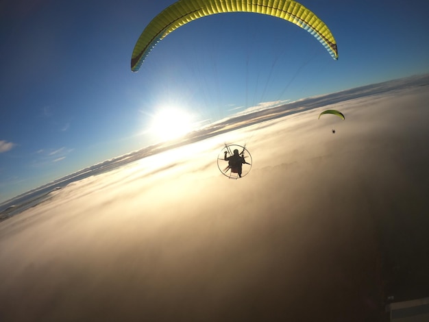 Vista en bajo ángulo de una persona en parapente contra las nubes