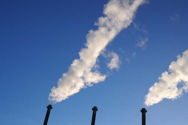 Vista de ángulo bajo de la pila de humo contra el cielo azul