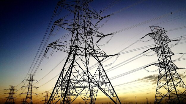 Foto vista de ángulo bajo de pilares eléctricos contra el cielo durante la puesta del sol