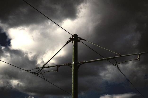 Foto vista de ángulo bajo de postes y cables contra un cielo nublado