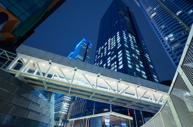Vista de ángulo bajo del puente de la pasarela y el edificio de oficinas del rascacielos, escena nocturna