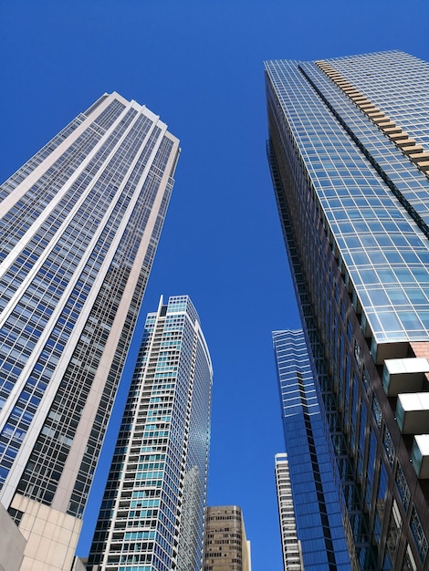 Foto vista en bajo ángulo de rascacielos contra un cielo azul claro