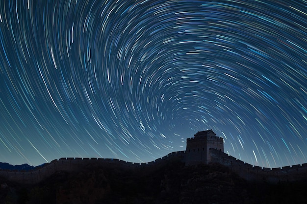 Vista de bajo ángulo del rastro de estrellas sobre la Gran Muralla de China por la noche
