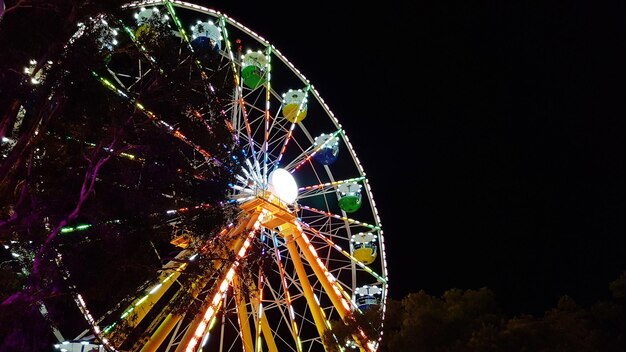 Foto vista de ángulo bajo de la rueda gigante iluminada contra el cielo por la noche