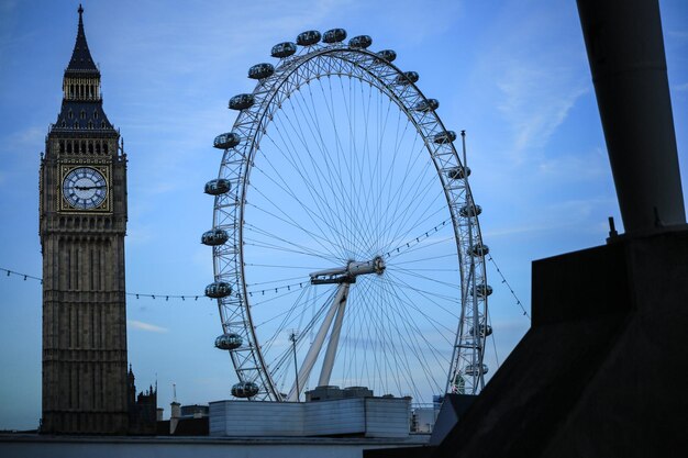 Foto vista de ángulo bajo de la rueda del milenio y el big ben contra el cielo en la ciudad