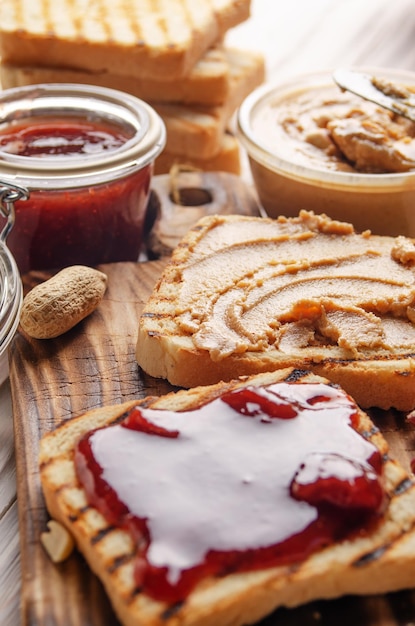 Vista de ángulo bajo en sándwiches de mantequilla de maní y mermelada en la tabla de cortar con tostadas a un lado. Concepto de alimentación saludable