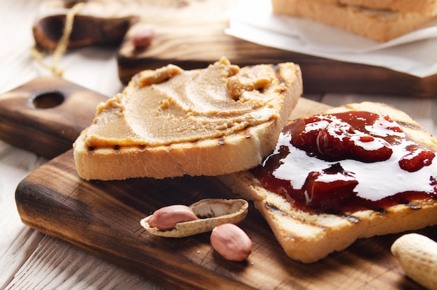 Vista de ángulo bajo en sándwiches de mantequilla de maní y mermelada en la tabla de cortar con tostadas a un lado. Concepto de alimentación saludable