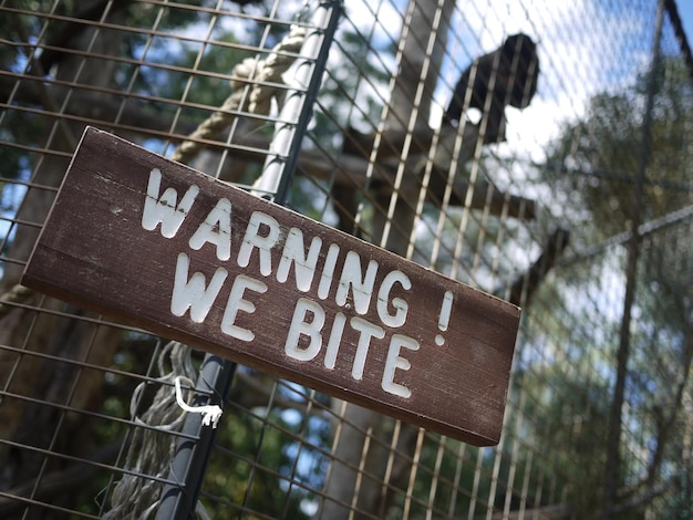 Vista en bajo ángulo de la señal de advertencia en la valla metálica en el zoológico