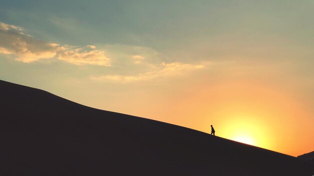 Foto vista de ángulo bajo de la silueta de un hombre caminando contra el cielo durante la puesta de sol