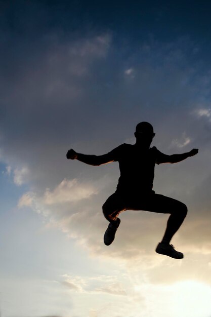 Foto vista en bajo ángulo de la silueta de un hombre saltando contra el cielo