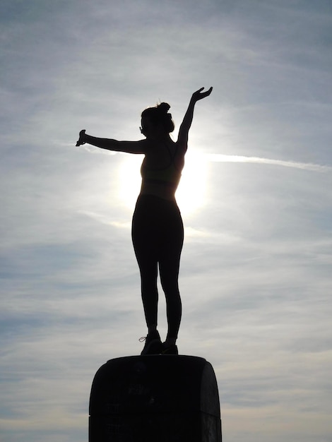 Foto vista de ángulo bajo de la silueta de una mujer joven de pie contra el cielo