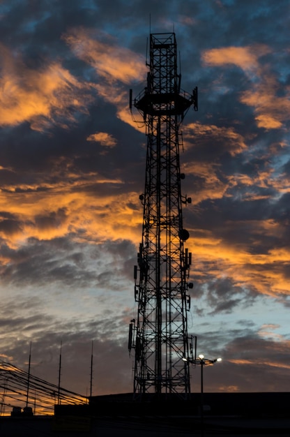 Vista en bajo ángulo de la silueta de la torre de comunicaciones contra el cielo nublado durante la puesta de sol