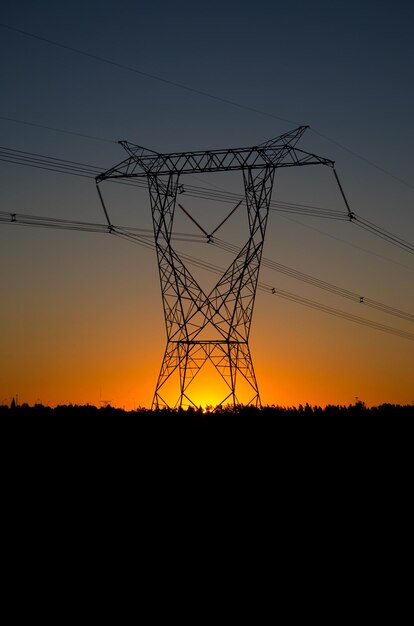 Foto vista de ángulo bajo de la silueta de la torre de electricidad contra el cielo durante la puesta del sol