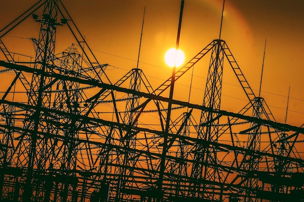Vista en bajo ángulo de las siluetas de las torres eléctricas contra el cielo naranja al atardecer