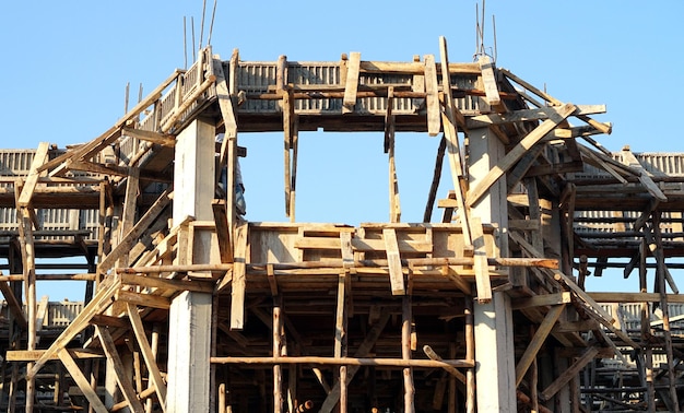 Vista de ángulo bajo del sitio de construcción contra el marco de madera del cielo para la casa de construcción de hormigón