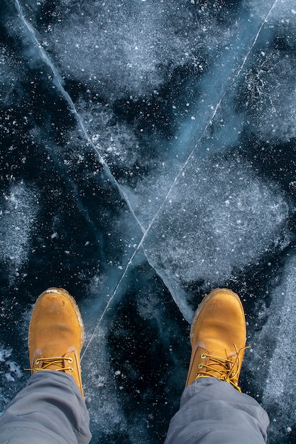 Vista de ángulo superior de pies de pie sobre hielo roto en el lago Baikal, Rusia