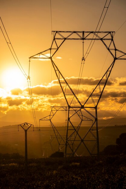 Vista de ángulo bajo de la torre de electricidad contra el cielo durante la puesta del sol