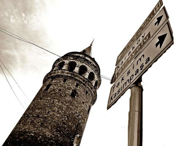 Vista en bajo ángulo de la torre de galata y las señales de tráfico contra el cielo