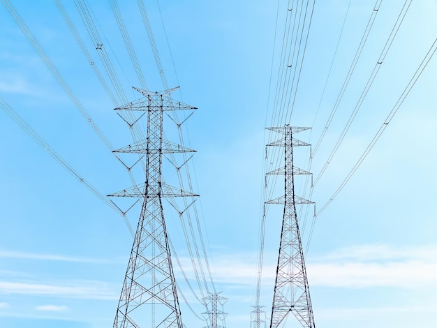 Foto vista en bajo ángulo de torres y cables de transmisión eléctrica de alta tensión contra el cielo azul