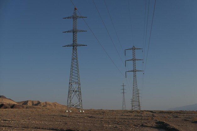 Foto vista en bajo ángulo de las torres eléctricas contra un cielo azul despejado