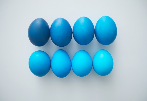 Vista anterior de hermosos huevos de Pascua azul robin dispuestos en una composición mínima sobre una superficie blanca, espacio de copia