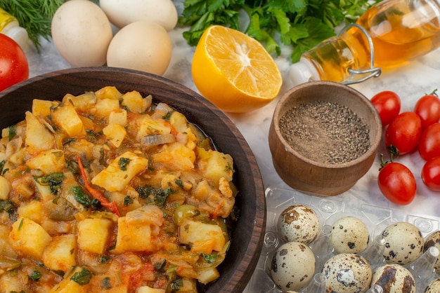 Vista anterior de la sabrosa comida con patatas en una toalla despojada roja botella de aceite caído paquetes verdes huevos pimienta