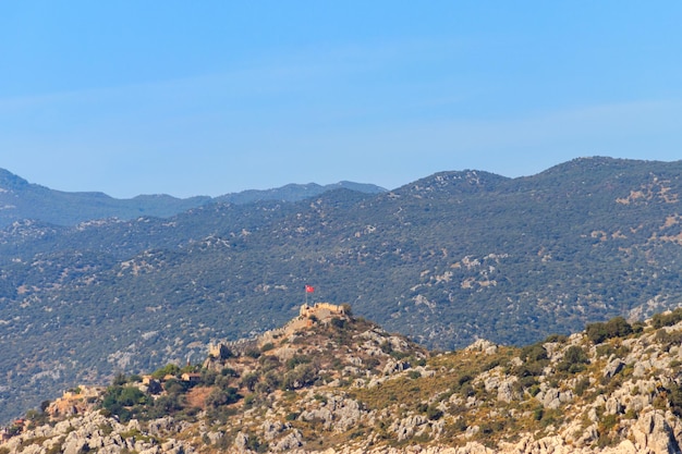 Foto vista de la antigua ciudad licia de simena con una fortaleza en un monte en la costa del mar mediterráneo en la provincia de antalya, turquía