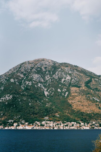 Vista de la antigua ciudad de Perast al pie de las montañas desde la orilla opuesta de la bahía