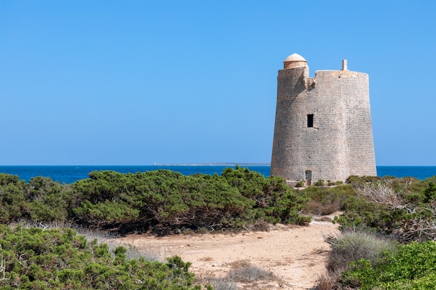 Foto vista de la antigua torre de observación torre de ses portes en la costa de la isla de ibiza.