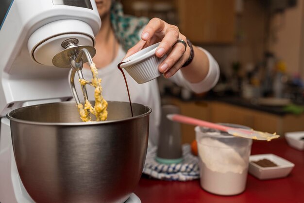 Vista aproximada da mão de um cozinheiro colocando extrato de baunilha em uma tigela para a preparação da receita caseira de alfajores argentinos