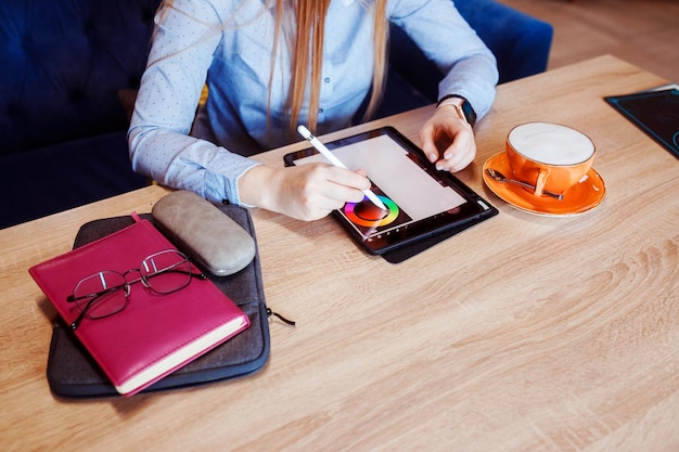 Foto vista aproximada das mãos femininas desenhando no tablet digital no ilustrador do café no trabalho