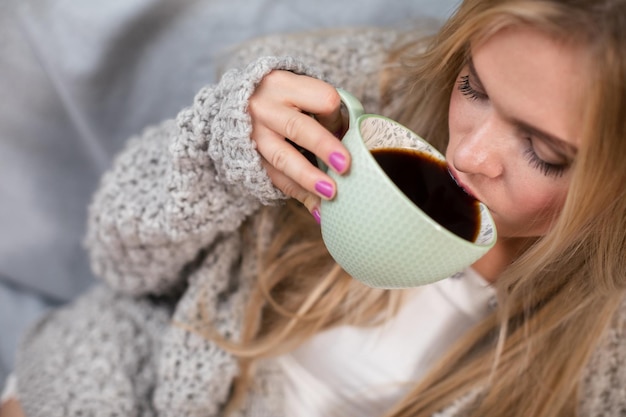 Vista aproximada de uma mulher bebendo seu café da manhã de uma xícara