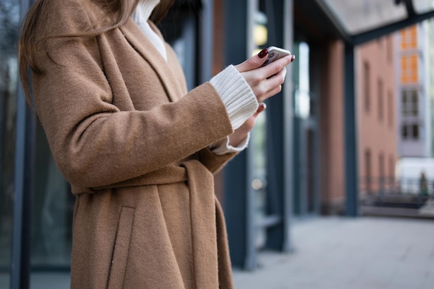 Vista aproximada de uma mulher com um smartphone nas mãos na rua