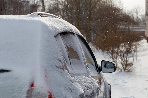 Vista aproximada do carro coberto de neve e neve à deriva na sua roda