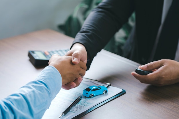 Vista aproximada mão do vendedor de carros apertando as mãos dos clientes depois de assinar o contrato de compra legalmente, conclusão bem sucedida das vendas de carros, contrato de compra,