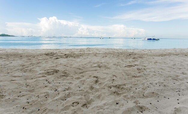 Vista desde la arena del Mar Caribe con botes y un hermoso cielo azul con nubes