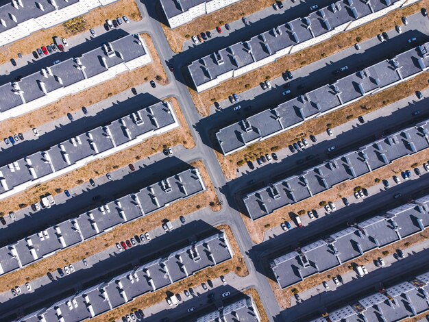 Vista de arriba hacia abajo de edificios residenciales de poca altura, céspedes, carreteras y estacionamientos.