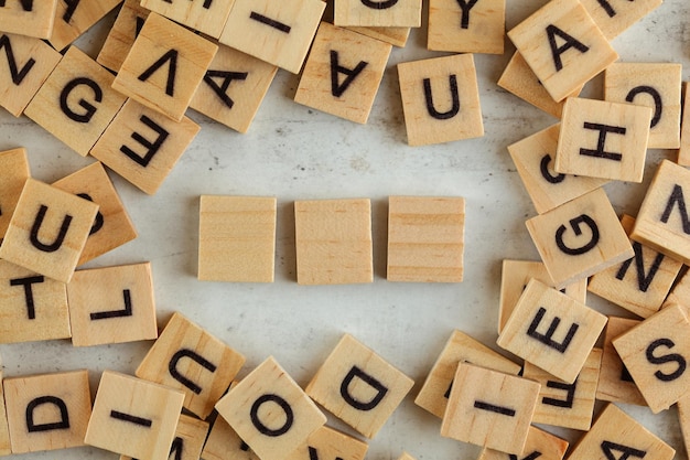 Vista de arriba hacia abajo, pila de bloques cuadrados de madera con letras en una pizarra blanca. Tres mosaicos vacíos para su texto.