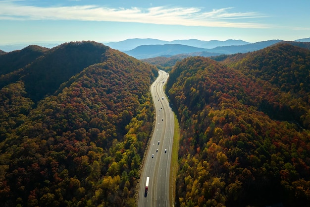 Vista desde arriba de la autopista I40 en Carolina del Norte que se dirige a Asheville a través de las montañas Apalaches en la temporada dorada de otoño con camiones y automóviles de conducción rápida Concepto de transporte interestatal