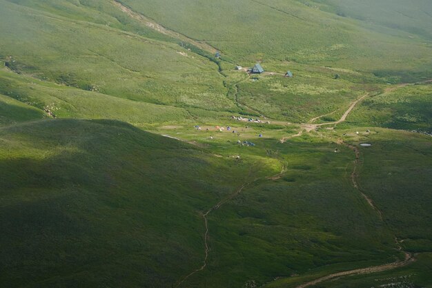 Vista desde arriba de un campamento de tiendas entre verdes prados alpinos